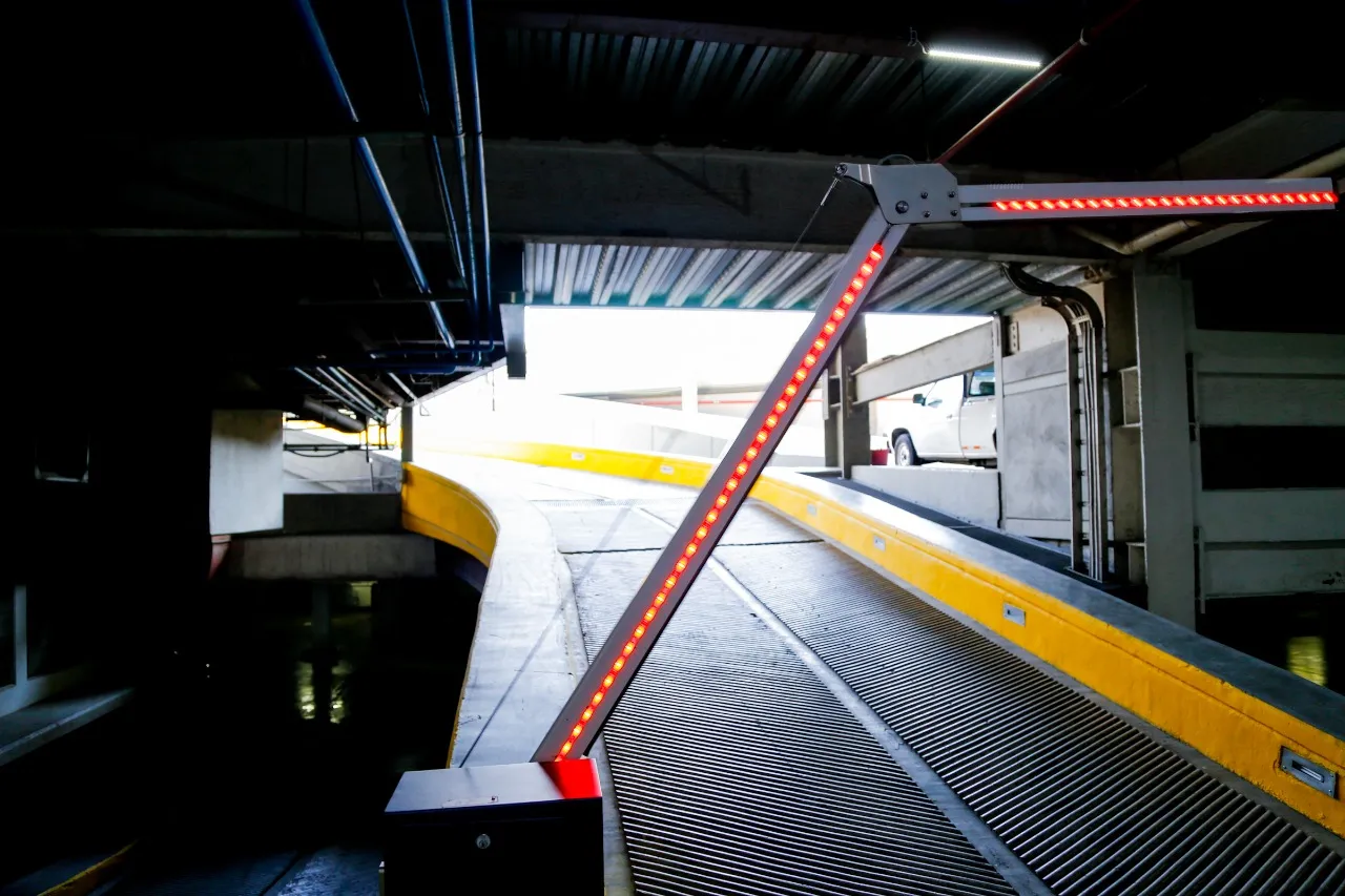 Pluma articulada con luz LED roja en la rampa de un estacionamiento